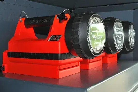 Portable industrial LED work lights stored on a metal shelf, providing reliable illumination for equipment maintenance, emergency response, and field operations.